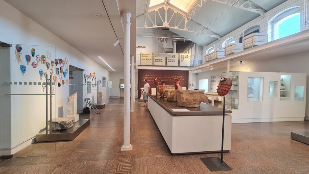 Sala do Museu de Lisboa – Teatro Romano com máscaras contemporâneas e vestígios arqueológicos romanos